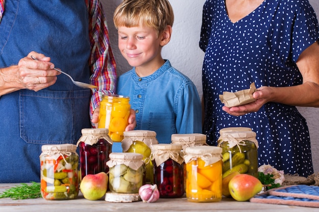 Happy senior people, grandmother, grandfather and young boy, grandson tasting homemade fruit compote. Preserved and fermented, pickled and marinated food concept. Harvest preservation, family time