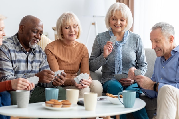 Photo happy senior people playing cards at nursing home