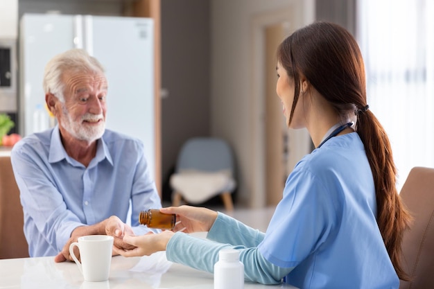 Счастливый пожилой взрослый на пенсии принимает таблетку или лекарство для лечения молодой женщины-врача из клиники