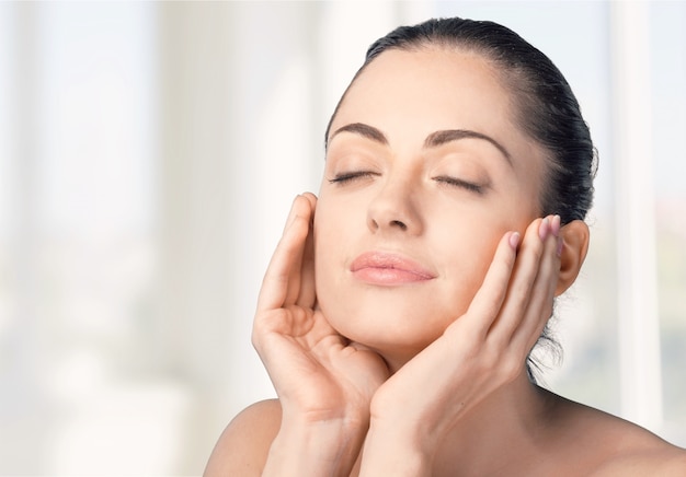 Happy senior woman applying anti-aging cream near mirror