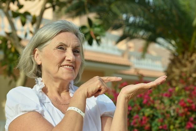 Happy Senior woman in autumn park pointing at something