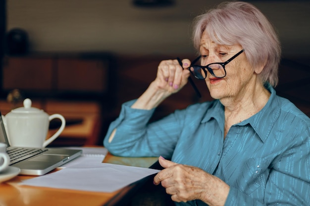 Счастливая пожилая женщина в кафе с чашкой напитка в социальных сетях без изменений