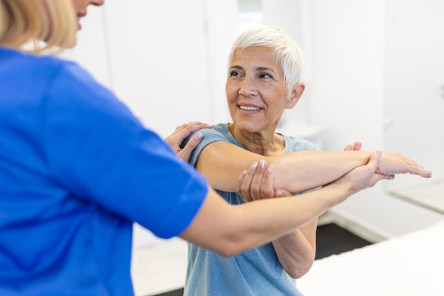 Foto una donna anziana felice che fa esercizio con un fisioterapista una vecchia signora in pensione che fa stretching delle braccia in clinica con l'aiuto di un personal trainer durante una sessione di riabilitazione