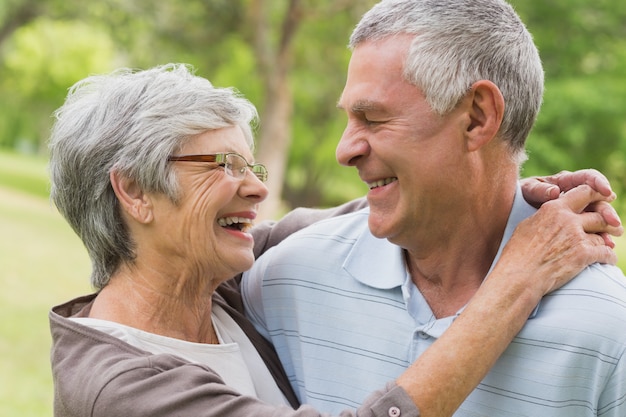 Happy senior woman embracing man at the park