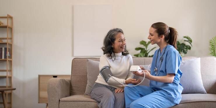 Photo happy senior woman having her blood pressure measured in a nursing home by her caregiver happy nurse measuring blood pressure of a senior woman in living room