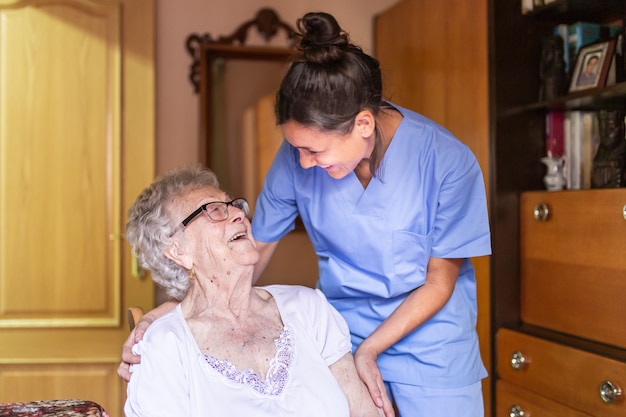 Happy Senior woman laughing with her caregiver at home