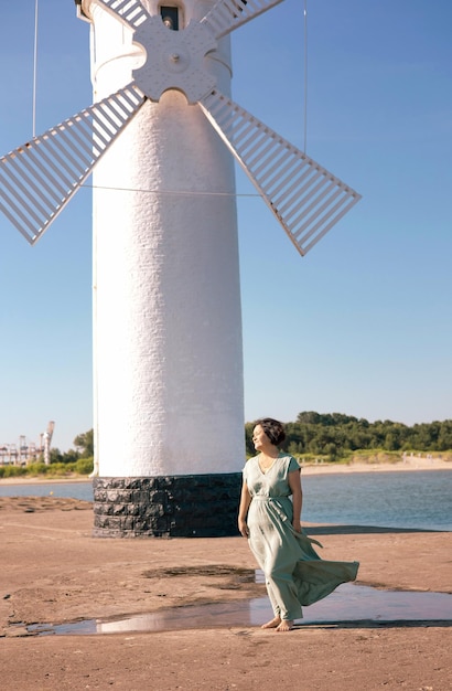 Happy senior woman in long dress walking on tropical island beach at summer sunset