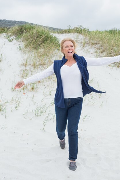 Photo happy senior woman running at beach