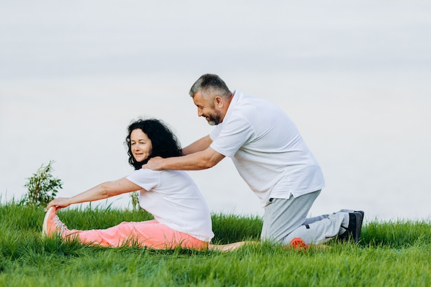 Happy senior woman   taking exercise outdoor and man doing massage for her  