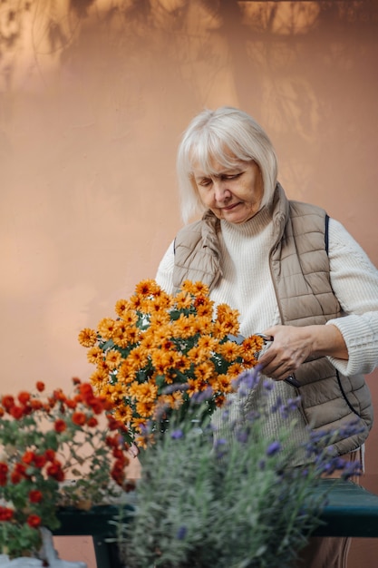 정원에서 화분에 심은 꽃을 이식 하는 행복 한 고위 여자.