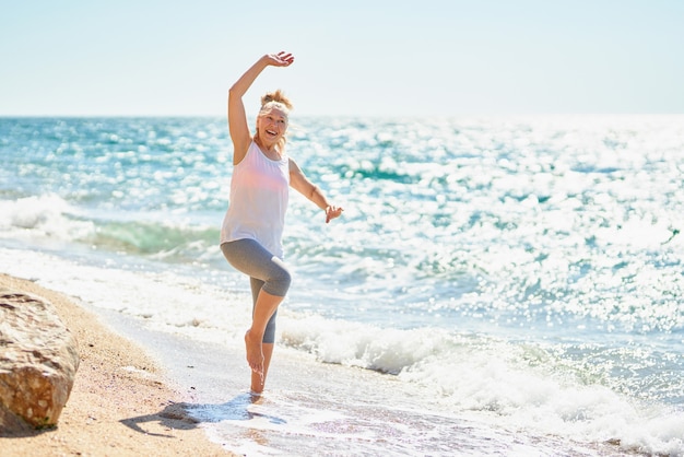 Happy senior woman walks by the sea.