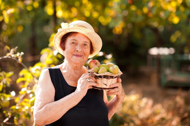 屋外で果物と幸せな年配の女性