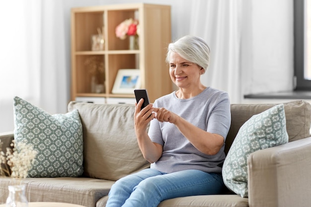 happy senior woman with smartphone at home