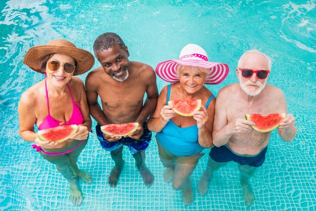 Photo happy seniors having party in the swimming pool  elderly friends at a pool party during summertime