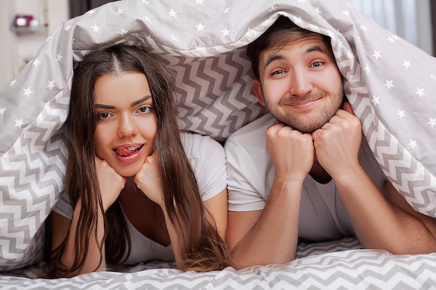 Happy sensual young couple lying in bed together