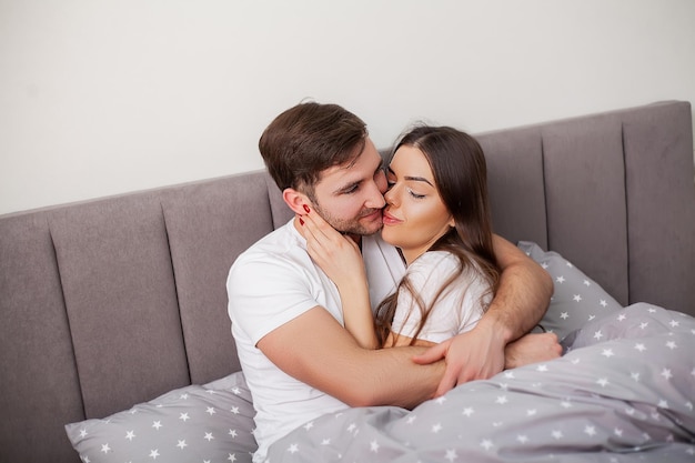 Photo happy sensual young couple lying in bed together