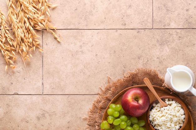 Happy Shavuot Background for Shavuot celebration Milk and cheese ripe wheat and fruits blue wooden background Dairy products over old cracked tile wall Shavuot concept Top view Mock up