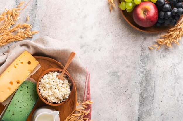 Happy Shavuot Background for Shavuot celebration Milk and cheese ripe wheat and fruits blue wooden background Dairy products over old grey table concrete background Shavuot concept Mock up