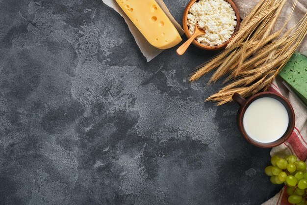 Felice shavuot sfondo per shavuot tradizionale celebrazione religiosa ebraica latte e formaggio grano maturo e frutta prodotti lattiero-caseari su vecchio sfondo grigio scuro concetto shavuot vista dall'alto mock up