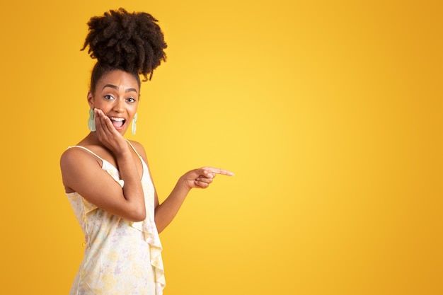 Happy shocked millennial african american woman pointing finger at empty space