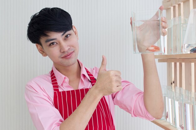 Happy Shop manager thumbs up and holding fish tank in a Pet Store