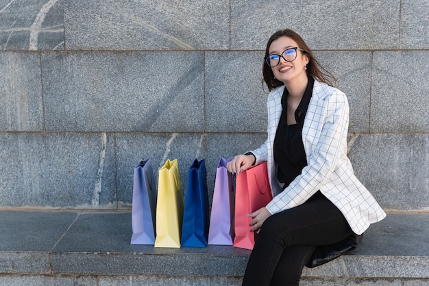 屋外で買い物袋がたくさんある幸せな買い物中毒の女性