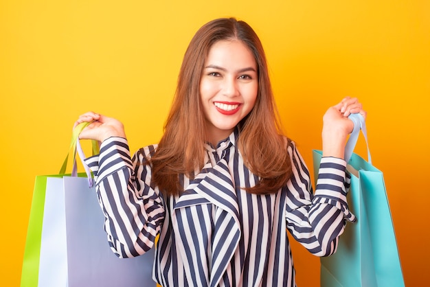 Happy shopping woman on yellow background 