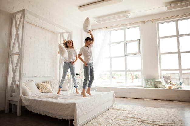 Happy sibling jumping on bed in bedroom