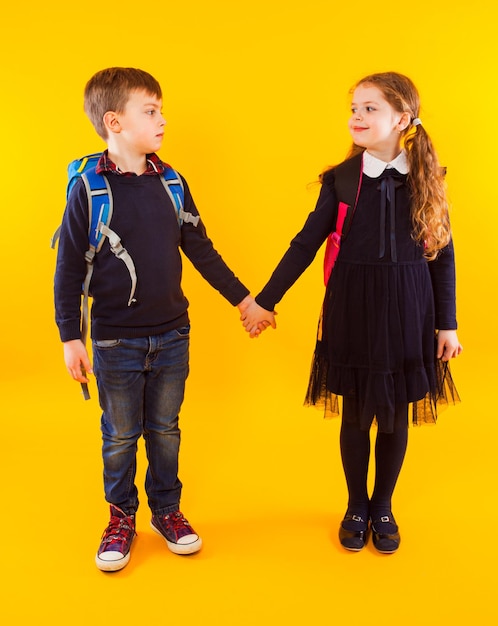 Happy siblings standing against yellow background