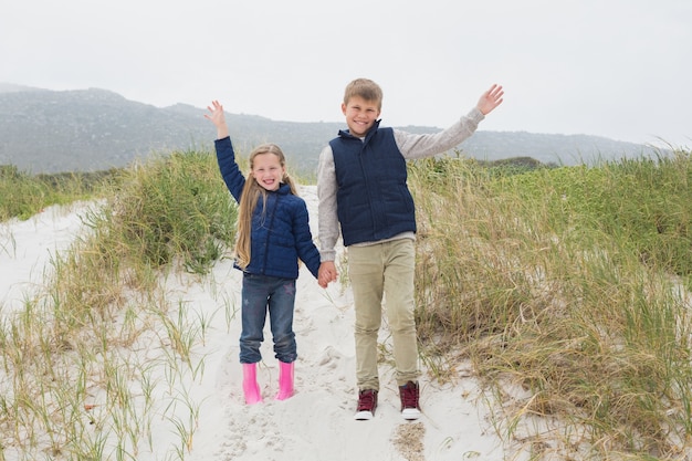 Happy siblings standing hand in hand at beach