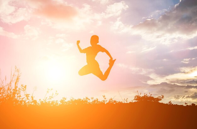 Happy silhouette boy jumping against sky during sunset