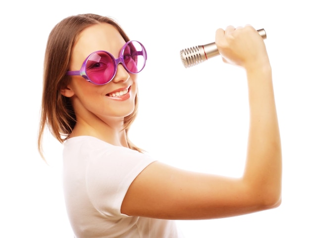 Happy singing girl Beauty woman wearing white tshirt and big sunglasses with microphone over white background ipster styl