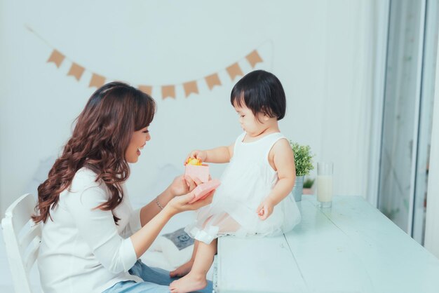 Happy single mother and curious child girl opening pink gift box together