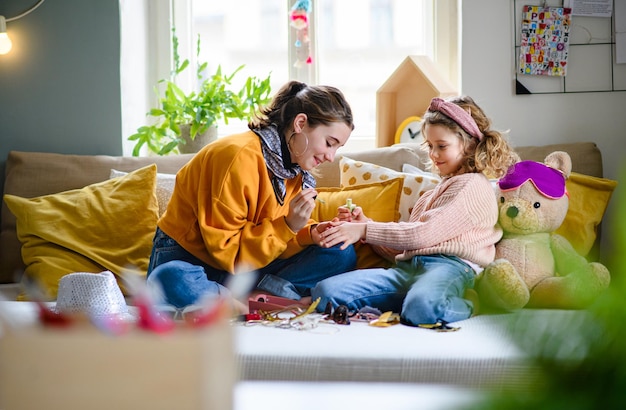 Photo happy sisters indoors at home, painting fingernails. lockdown concept.