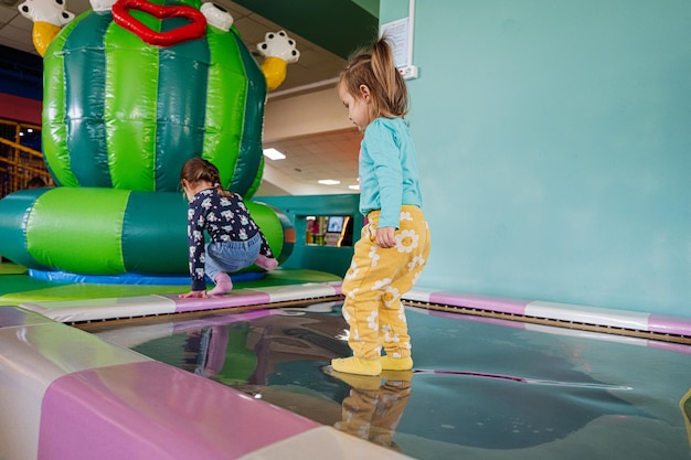 Happy sisters playing at indoor play center playground in water trampoline