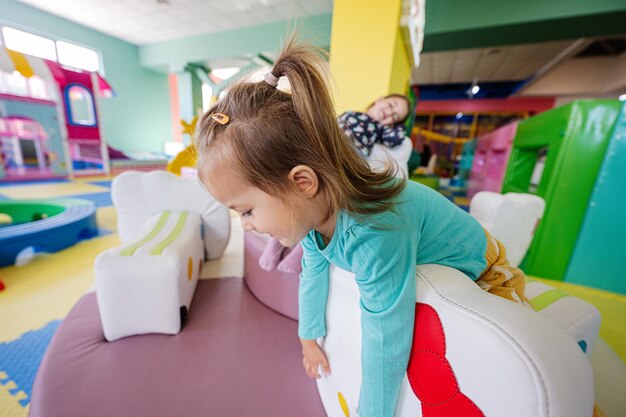 屋内プレイ センターの遊び場で遊んで幸せな姉妹