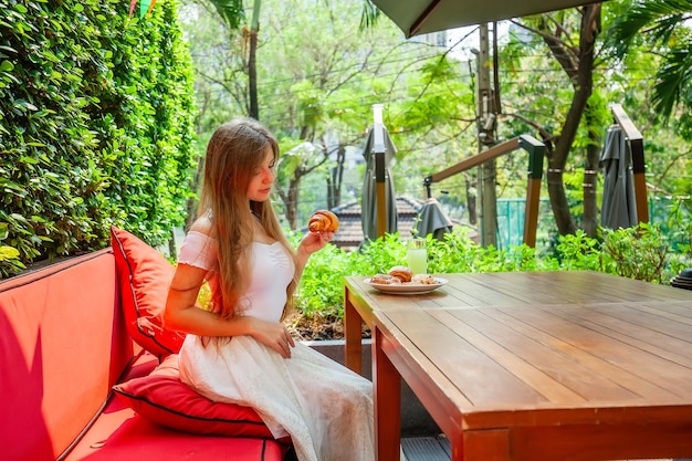 幸せなスリムな若い女性は、新鮮なパン屋の食べ物を食べることをお楽しみください空腹の女性はプレートを取る