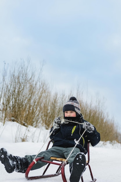 冬の雪に覆われた中庭で幸せな小さな男の子