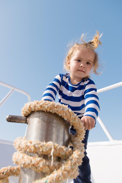 Happy small boy on yacht. Sea trip concept. funny kid in striped marine shirt. journey discovery. Transportation. summer vacation. childhood happiness. small sailor on sea boat. sea transport.