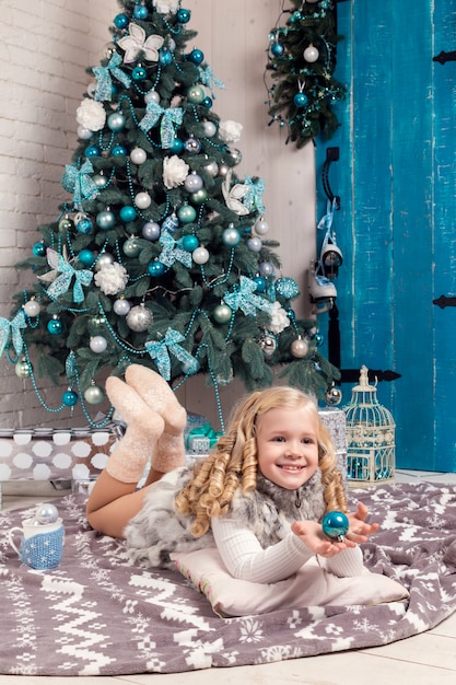 現在のドレスで幸せな小さな女の子がクリスマスを持っています