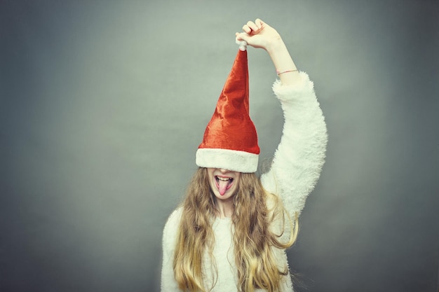 サンタの帽子をかぶった幸せな小さな女の子はクリスマスを持っています