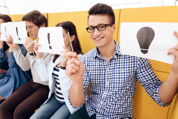 Happy smart guy holds sheet with image of having idea sitting on boxes.