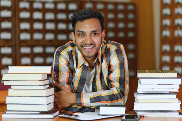 図書館で幸せなスマートなインド人またはアラビア人の混血男子大学生