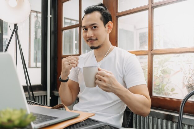 仕事とマスクを着用しながらコーヒーを飲む男の幸せと笑顔の顔