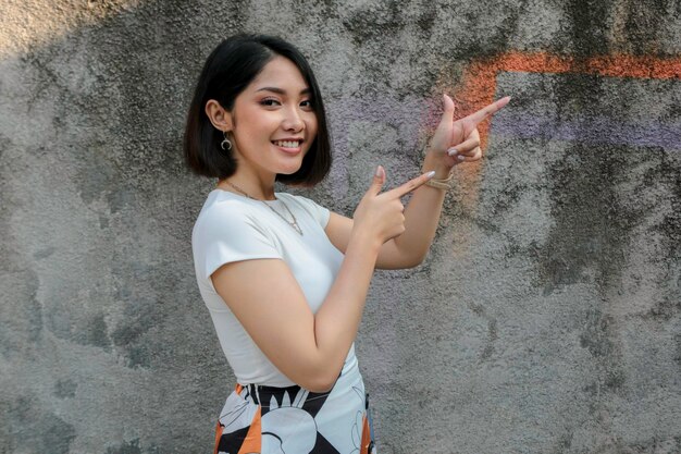 Happy and smile face with smile of young Asian girl with hand point on empty space