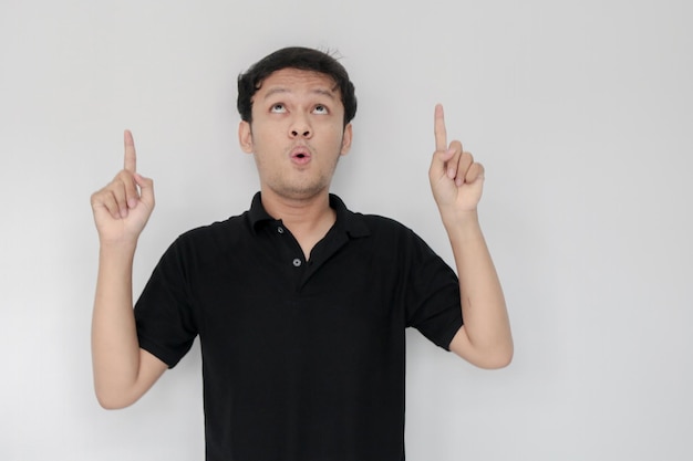 Happy and smile face with smile of young Asian man in black shirt with hand point on above empty space