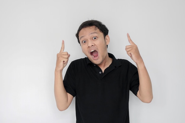 Happy and smile face with smile of young Asian man in black shirt with hand point on above empty space