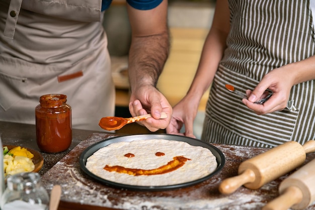 Happy smile love couple made pizza with sauce fun face on pizza before cook stove or oven in family relax activity in kitchen room with food and drink for healthy dinner