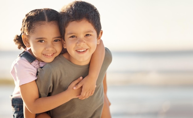 Happy smile and portrait of siblings at the beach hugging and playing while on summer vacation Happiness ocean and brother giving his sister a piggyback ride while on a seaside family holiday