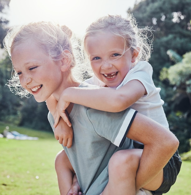 Happy smile and siblings in an outdoor park during summer having fun and playing in nature Happiness excited and girl children on an adventure giving a piggy back ride outside in a green garden